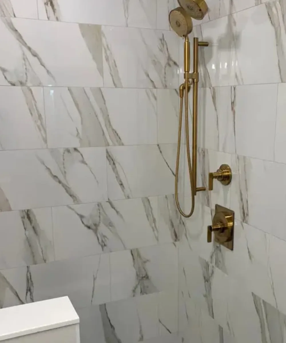 Gold shower fixture and marble-look tile installation